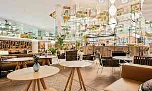 Moderne og elegant indrettet café med siddegrupper og planter. (AI-genereret tekst)