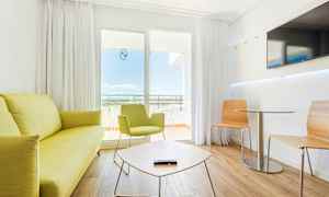 Et moderne hotelværelse med lyse møbler og siddegruppe. (AI-genereret tekst)