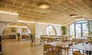 Interiør af en restaurant med stenbuer, moderne møbler og dekorative planter. (AI-genereret tekst)