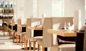 Interiør af en lys og elegant restaurant med dækkede borde og stole. (AI-genereret tekst)