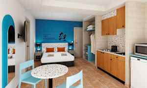 Hotelværelse med dobbeltseng, blå væg, spisebord og køkken. (AI-genereret tekst)