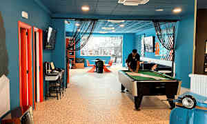 Et indendørs værelse med et billardbord, siddepladser og dekorationer i farverige detaljer. (AI-genereret tekst)