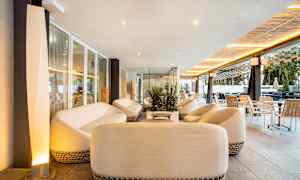 Et afslapningsområde med hvide sofaer og borde, omgivet af glasvægge og moderne møbler. (AI-genereret tekst)