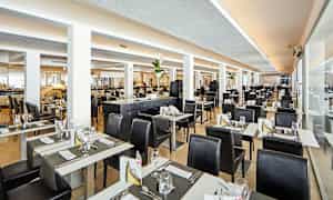 Et lyst og moderne restaurantområde med dækkede borde og sorte stole. (AI-genereret tekst)