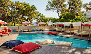 En udendørs pool omgivet af liggestole og parasoller. (AI-genereret tekst)