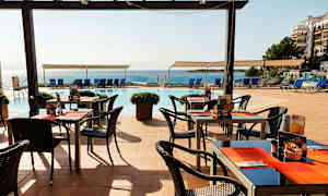 Udendørs servering med borde og stole nær pool og hav. (AI-genereret tekst)