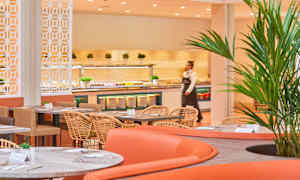 Billede af en spisesal med moderne møbler, hvor borde med stole er placeret. En buffet med forskellige retter ses i baggrunden. (AI-genereret tekst)