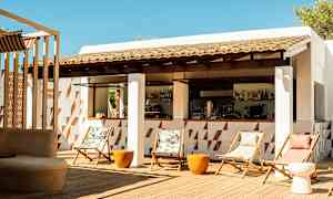 En udendørs bar med stole og borde på en trægulvterrasse. (AI-genereret tekst)