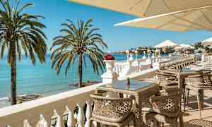 En terrasse med udsigt over havet, liggestole og parasoller. (AI-genereret tekst)