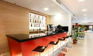 En moderne hotelbar med røde paneler, sort bordplade og flere barstole. (AI-genereret tekst)