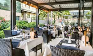 Udendørsrestaurant med opdækkede borde og dekorerede stole. (AI-genereret tekst)