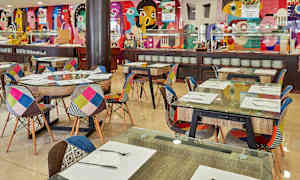 Indretning af en restaurant med farverige stole og dekorerede vægge. (AI-genereret tekst)