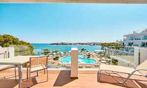 Hotelværelsesudsigt mod poolområde og hav. (AI-genereret tekst)