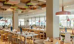 Restaurant med lyse møbler og dekoreret loft. (AI-genereret tekst)