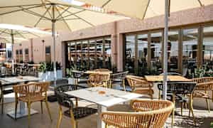 Udendørs servering med borde, stole og parasoller. (AI-genereret tekst)