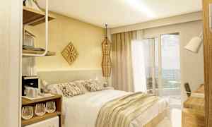 Et hotelværelse med en dobbeltseng, lyst interiør og et vindue ud imod en altan. (AI-genereret tekst)