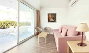 Sofa med pink betræk, sofabord, to stole og vindue med udsigt til terrassen. (AI-genereret tekst)