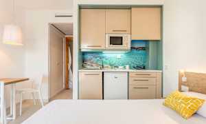 Et enkelt hotelværelse med et lille køkken og en seng. (AI-genereret tekst)