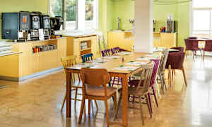 En spisesal med dækket bord og farverige stole. (AI-genereret tekst)