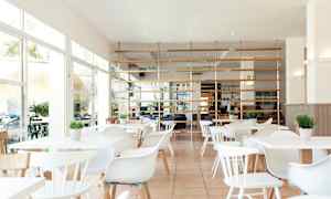 Lys og moderne restaurant med hvide møbler og grønne planter. (AI-genereret tekst)