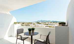 Altan med bord og stole, udsigt over omkringliggende bygninger og bjerge. (AI-genereret tekst)