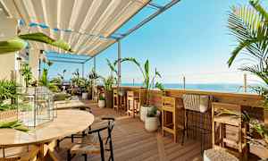 En terrasse med havemøbler og planter med udsigt over havet. (AI-genereret tekst)