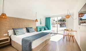 Hotelværelse med en dobbeltseng, en sofa med puder, et lille spiseområde og en altan. (AI-genereret tekst)