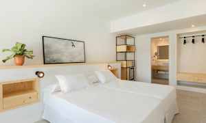 Et lyst hotelværelse med en dobbeltseng og træindretning. (AI-genereret tekst)