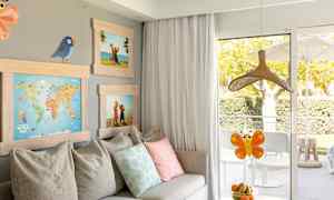 Et rum med en sofa, puder, billeder samt et bord med en skål med frugt foran en altandør. (AI-genereret tekst)