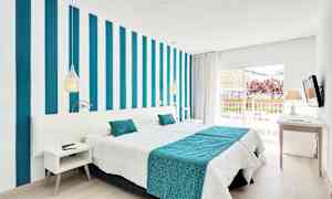 Et moderne hotelværelse med stribet væg, hvidt og turkis sengetøj samt en balkon med udsigt. (AI-genereret tekst)