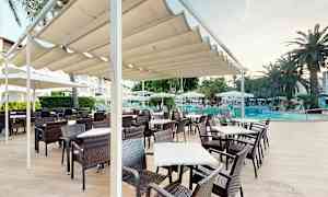 En udendørs terrasse med borde og stole under en pergola tæt ved en pool. (AI-genereret tekst)