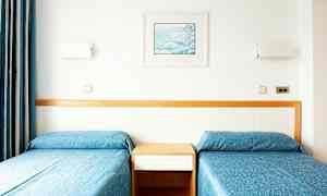 To enkeltsenge med blå sengetæpper og en træpanel bagved. (AI-genereret tekst)