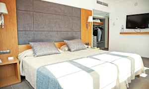 Billede der viser et moderne hotelværelse med en dobbeltseng, et garderobeskab og et vægmonteret TV. (AI-genereret tekst)