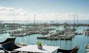 En udsigt over en havn med bord og stole i forgrunden. (AI-genereret tekst)