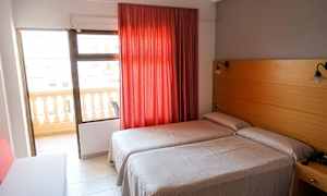 Hotelværelse med to enkeltsenge, rød gardin og altan. (AI-genereret tekst)