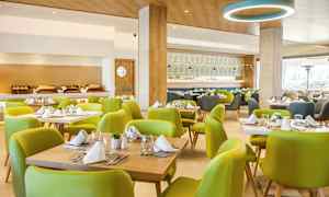 Interiør af en restaurant med grønne stole og dækkede borde. (AI-genereret tekst)