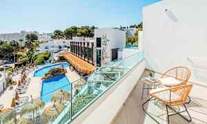 Udsigt fra en balkon med to stole og et bord mod en pool og bygninger omgivet af grønne områder. (AI-genereret tekst)