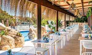 En terrasse restaurant med dækkede borde ved en pool. (AI-genereret tekst)