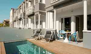 Bygninger med terrasse ved siden af en lille pool. (AI-genereret tekst)