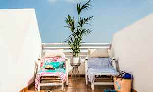 To liggestole med håndklæder og puder står på en terrasse med en plante potte mellem dem. (AI-genereret tekst)