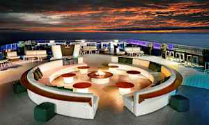 En tagterrasse med siddepladser, sofagrupper og en central opstilling med ild. (AI-genereret tekst)