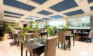 Et elegant restaurantområde med borde og stole, dekoreret med grønne planter. (AI-genereret tekst)