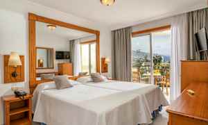 Hotelværelse med to enkeltsenge, et spejl, en TV og en balkon med siddeplads og udsigt. (AI-genereret tekst)