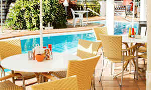 Udendørsområde med borde og stole ved en pool. (AI-genereret tekst)