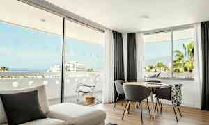 Et lyst værelse med store vinduer med udsigt over havet og naturen. (AI-genereret tekst)