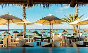 Udendørs serveringsområde ved stranden med parasoller og havudsigt. (AI-genereret tekst)