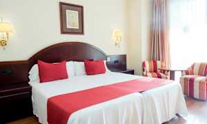 Dobbeltværelse med rødt interiør og to lænestole. (AI-genereret tekst)