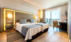 Et hotelværelse med to enkeltsenge, moderne møbler og en balkon med udsigt. (AI-genereret tekst)