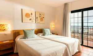 To enkeltsenge med hvidt sengetøj i et rum med udsigt mod en altan. (AI-genereret tekst)