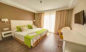 Hotelværelse med dobbeltseng, grønne detaljer og moderne indretning. (AI-genereret tekst)